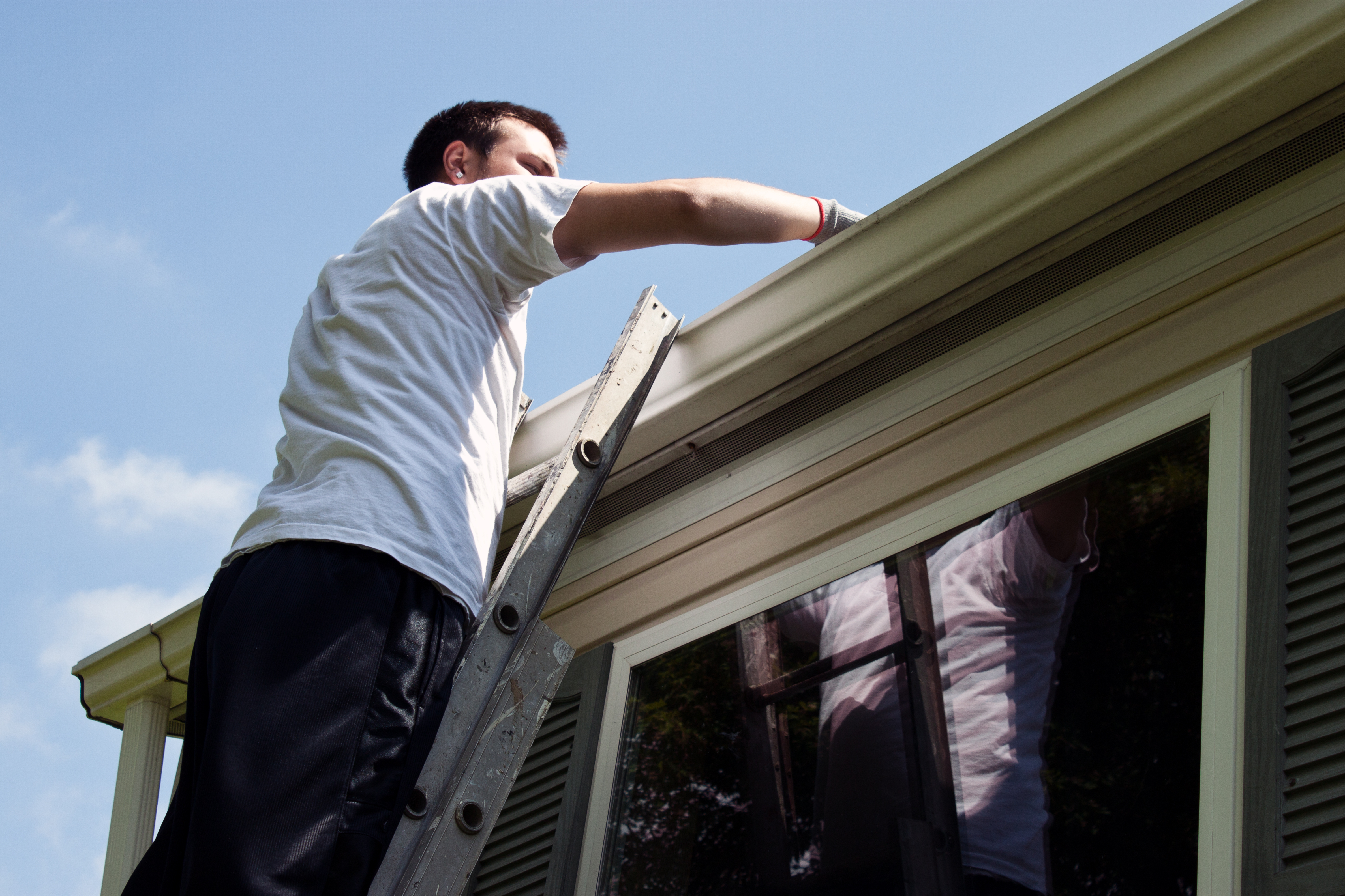 man cleaning debris from gutters