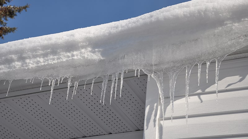 Man maintaining his gutters during winter season