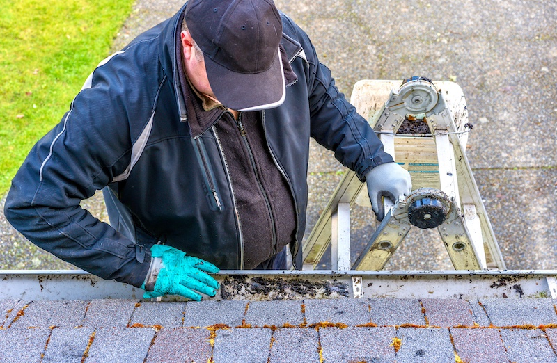 man on ladder cleaning gutters